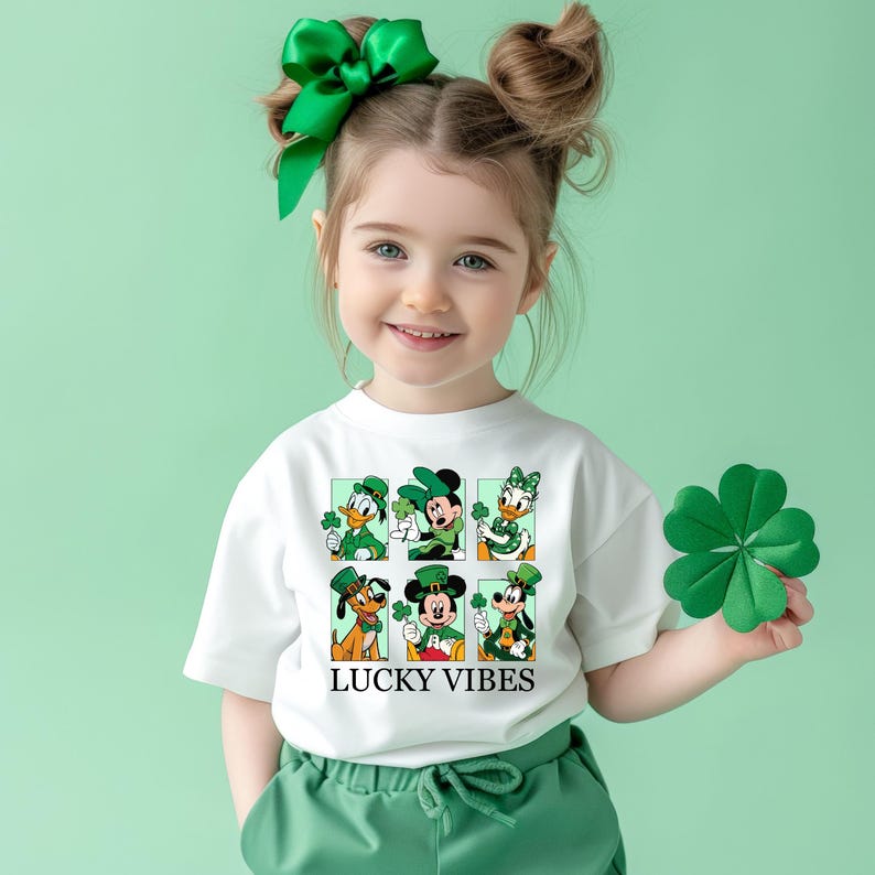 May include: A white t-shirt with a green shamrock design featuring Mickey Mouse, Minnie Mouse, Donald Duck, Goofy, and Pluto. The shirt has the text "LUCKY VIBES" printed on the front.