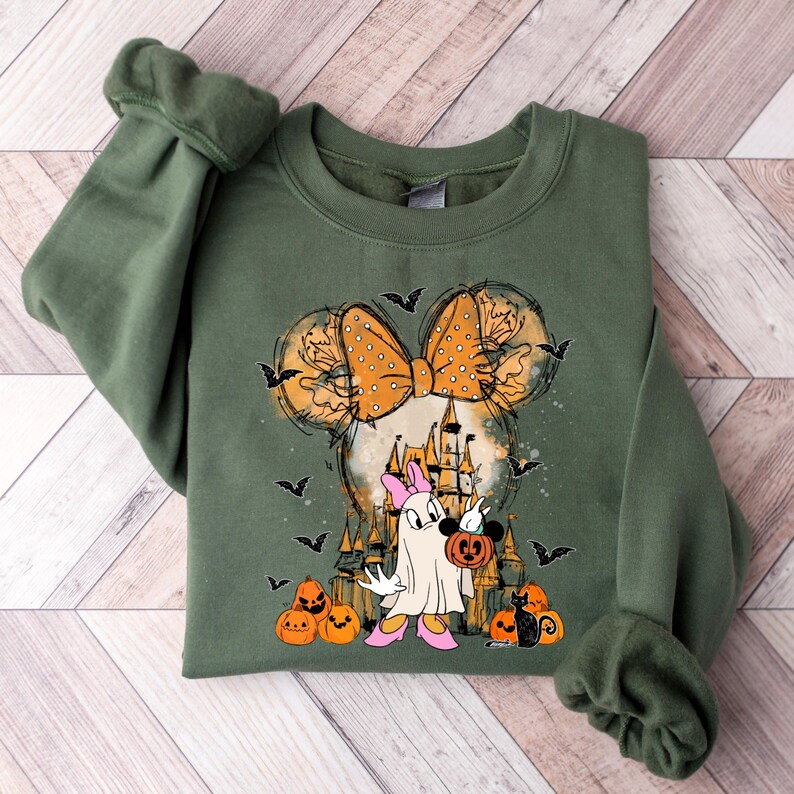 May include: Green sweatshirt with a Halloween-themed graphic featuring a cartoon character with a bow, a ghost holding a pumpkin, and a black cat. The graphic is surrounded by bats and pumpkins.
