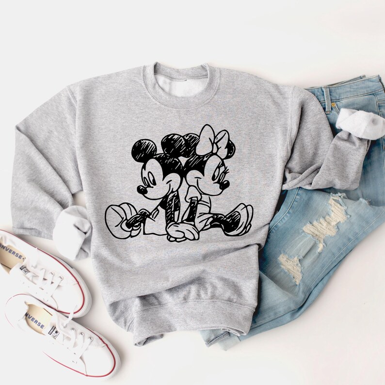 May include: A gray sweatshirt with a black and white illustration of Mickey Mouse and Minnie Mouse holding hands. The illustration is in a cartoon style.