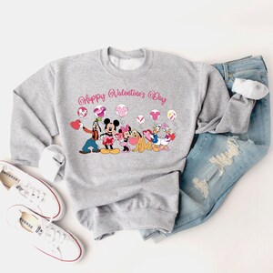 May include: Gray sweatshirt with a pink "Happy Valentine's Day" graphic featuring Mickey Mouse, Minnie Mouse, Goofy, Pluto, and Donald Duck holding hearts and balloons.