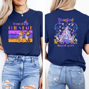 May include: A navy blue t-shirt with a graphic of Chip and Dale in front and a graphic of Disneyland's castle with Mickey Mouse and friends on the back. The text on the front says "Disneyland 70 Chip 'n Dale". The text on the back says "Disneyland 70 magical years".