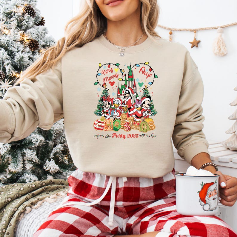 May include: Beige crewneck sweatshirt with a colorful Christmas graphic featuring Disney characters. The design includes the text "Very Merry" and "Christmas Party 2025". The graphic showcases a castle, Christmas trees, and candy canes.
