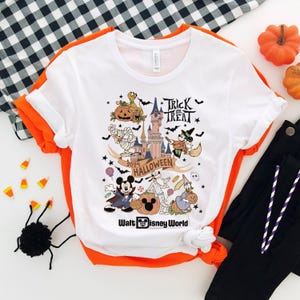 May include: White t-shirt with a colorful graphic of Mickey Mouse and other Disney characters celebrating Halloween at Walt Disney World. The graphic includes the text "Trick or Treat", "2024 Halloween", and "Walt Disney World".