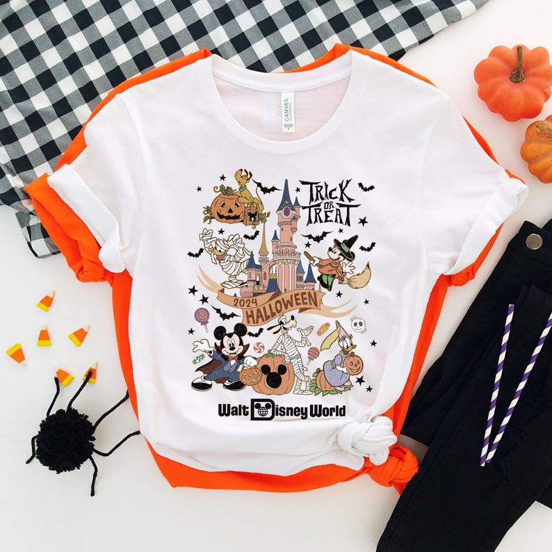 May include: White t-shirt with a colorful graphic of Mickey Mouse and other Disney characters celebrating Halloween at Walt Disney World. The graphic includes the text "Trick or Treat", "2024 Halloween", and "Walt Disney World".
