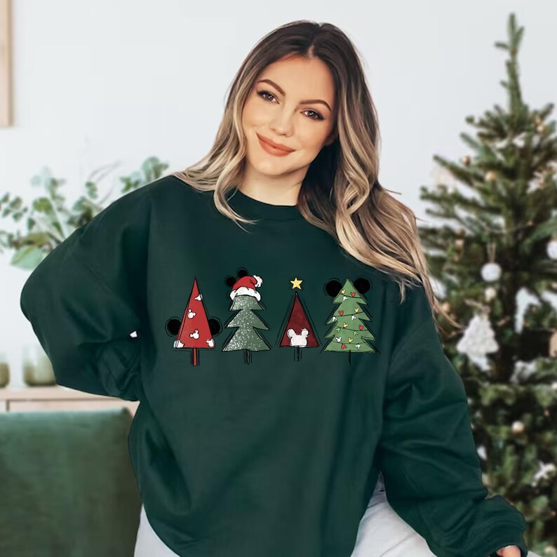 May include: A dark green sweatshirt with a Christmas tree design featuring Mickey Mouse characters. The trees are decorated with ornaments and a star on top.