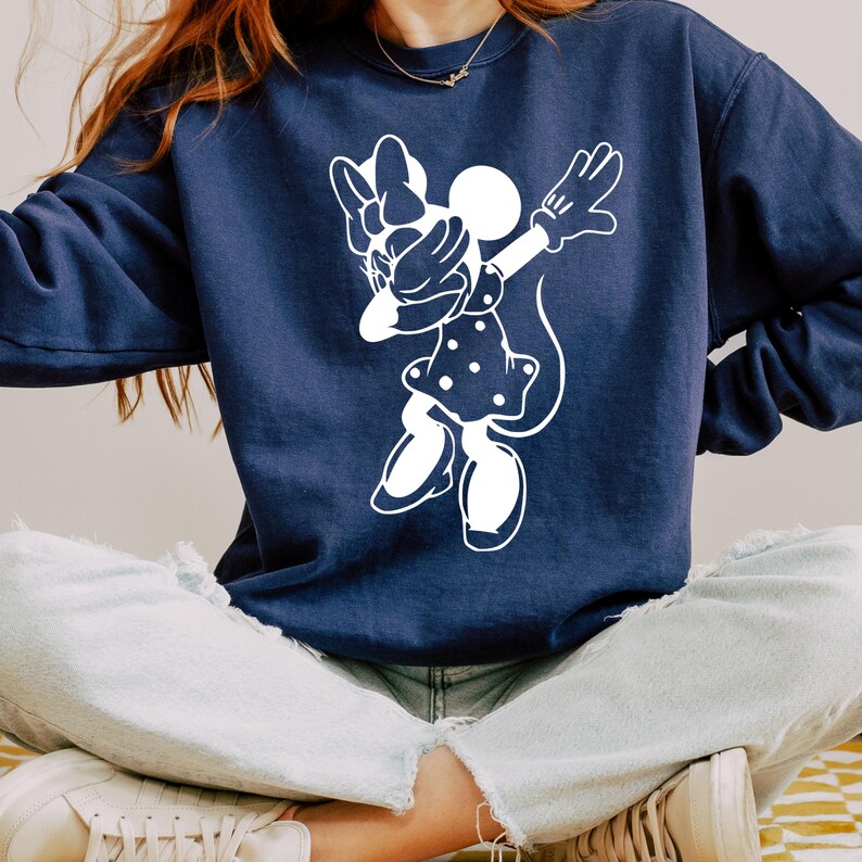 May include: A navy blue sweatshirt with a white graphic of a cartoon mouse doing the dab. The mouse is wearing a polka dot dress and has a bow on its head.