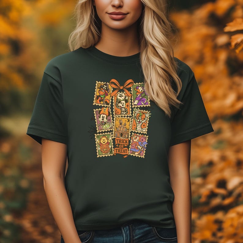 May include: Dark green t-shirt featuring a collage of Halloween-themed postage stamps. The stamps depict various characters and the words "Trick or Treat". A large orange bow is at the top of the collage.