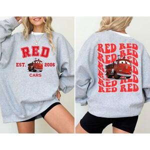 May include: A gray sweatshirt with a red graphic print of a fire truck and the text "RED EST. 2006 CARS" on the front. The back of the sweatshirt has a red graphic print of the text "RED RED RED RED RED RED RED RED RED RED" in a repeating pattern.