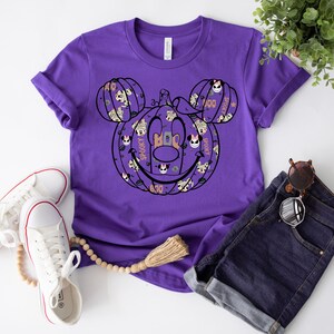 May include: Purple t-shirt featuring a Mickey Mouse pumpkin design. The pumpkin is made up of smaller Mickey Mouse faces with the words "Boo", "Spooky", and "Boo" on it.