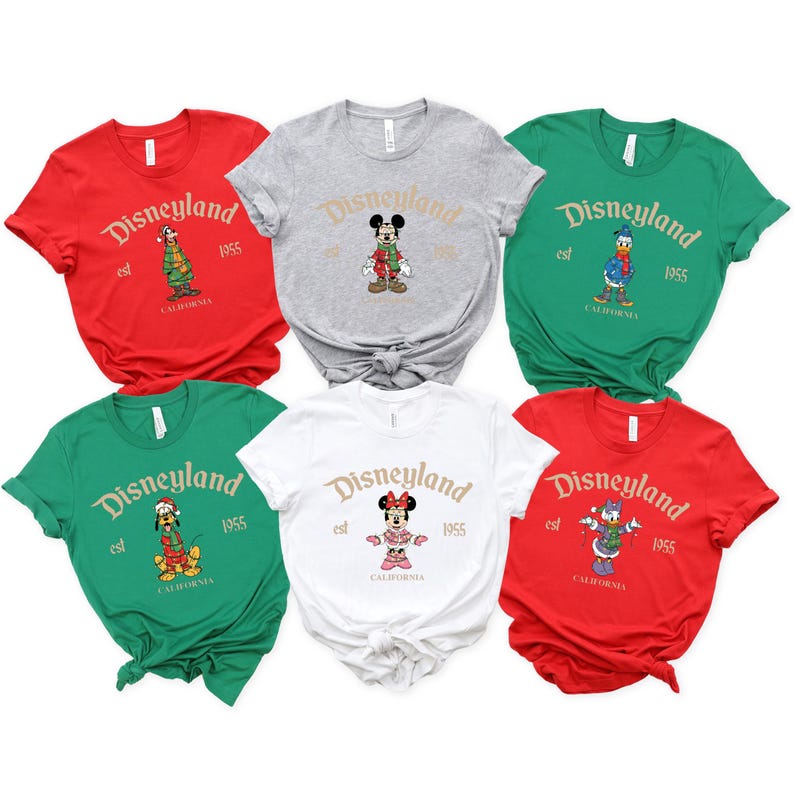 May include: A collection of six short-sleeved t-shirts featuring Disneyland graphics. Each shirt displays the Disneyland logo, the year 1955, and a character illustration. The shirts are in red, gray, green, and white.