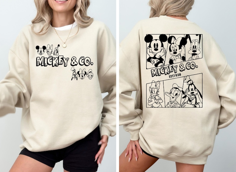 May include: A beige sweatshirt with a black and white graphic print of Mickey Mouse and friends. The front of the sweatshirt says "Mickey & Co.". The back of the sweatshirt has a larger graphic print of Mickey Mouse, Minnie Mouse, Donald Duck, and Goofy. The text on the back says "Mickey & Co. Est. 1928."