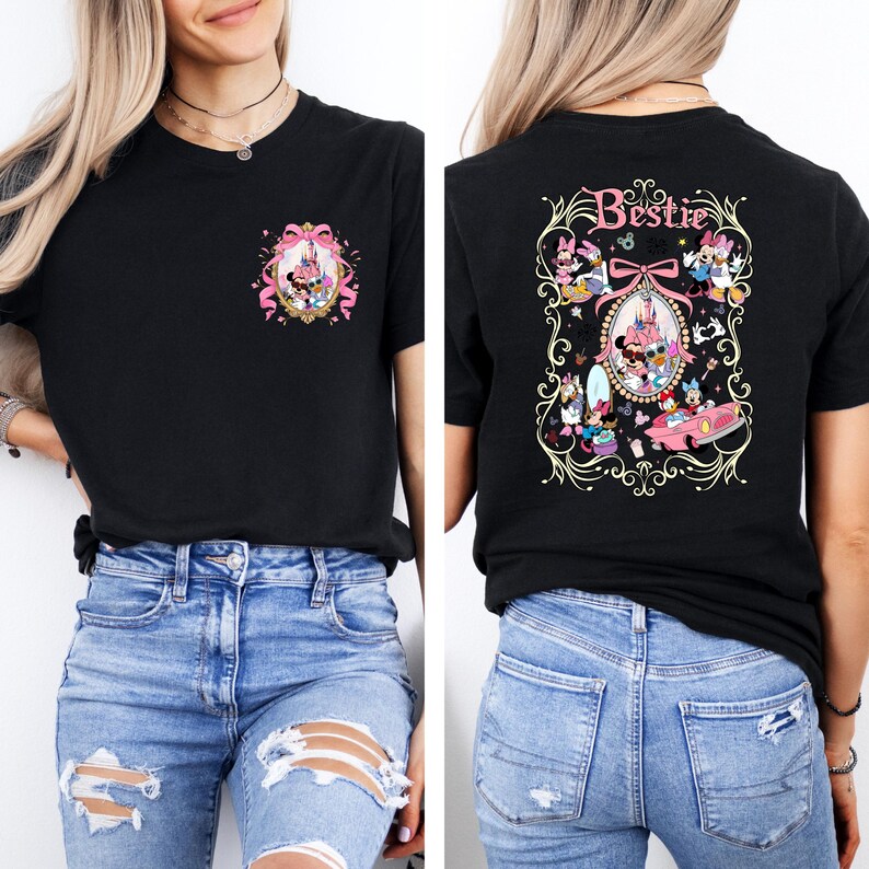 May include: Black t-shirt with a pink and gold design featuring Disney characters on the back. The design includes the word "Bestie" and a mirror with a pink bow. The front of the shirt has a smaller version of the design.