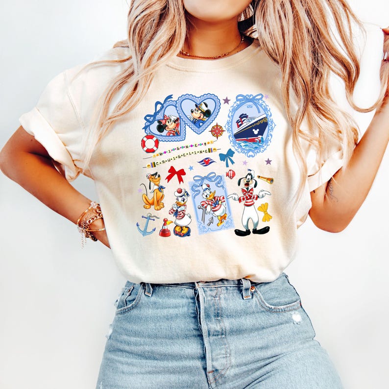 May include: A white t-shirt with a nautical theme featuring Mickey Mouse, Minnie Mouse, Donald Duck, Goofy, and a cruise ship. The design includes hearts, anchors, bows, and a life preserver.