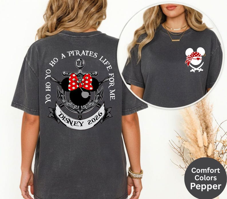 May include: Dark grey t-shirt with a pirate-themed design. The back features an anchor with Minnie Mouse ears and a red bow, the text "YO HO HO A PIRATES LIFE FOR ME" and "DISNEY 2026". The front has a pirate Mickey Mouse head.