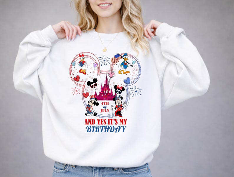 May include: White sweatshirt featuring a colorful graphic of Disney characters celebrating the 4th of July. The design includes Mickey and Minnie Mouse, Donald Duck, and Daisy Duck, with fireworks and a castle. Text reads "AND YES IT'S MY BIRTHDAY".