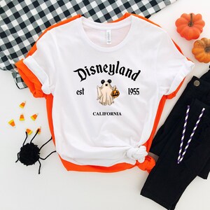 Puede incluir: Camiseta blanca con un gr&aacute;fico negro de un fantasma sosteniendo una calabaza y el texto "Disneyland est 1955 CALIFORNIA".