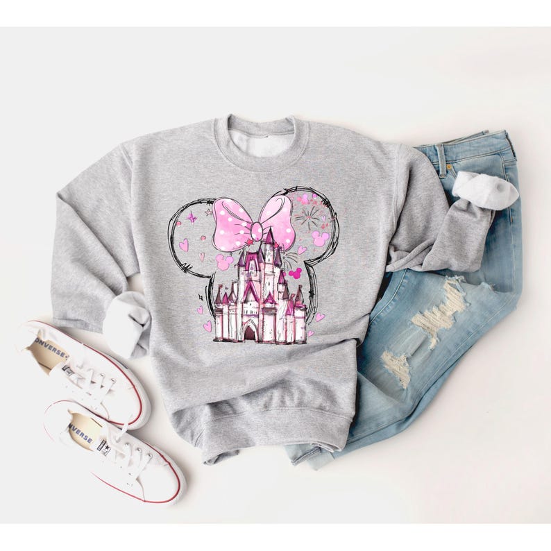 May include: A gray sweatshirt with a pink bow and a pink castle graphic. The castle is surrounded by hearts and fireworks.