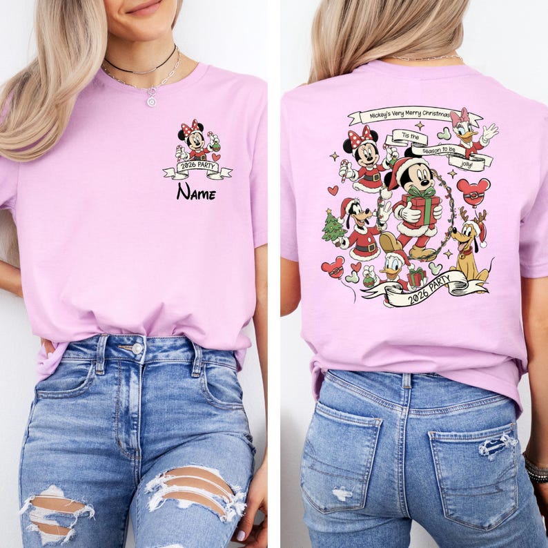 May include: A light pink t-shirt featuring a front and back design. The front has a Minnie Mouse graphic with the text "2026 PARTY" and "NAME". The back displays Mickey Mouse and friends with the text "Mickey's Very Merry Christmas" and "2026 PARTY".
