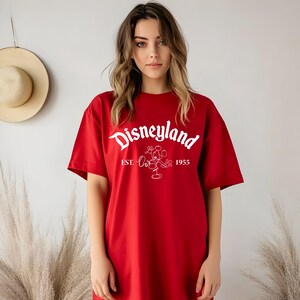 May include: Red t-shirt with a white graphic of Mickey Mouse and the text "Disneyland Est. 1955".