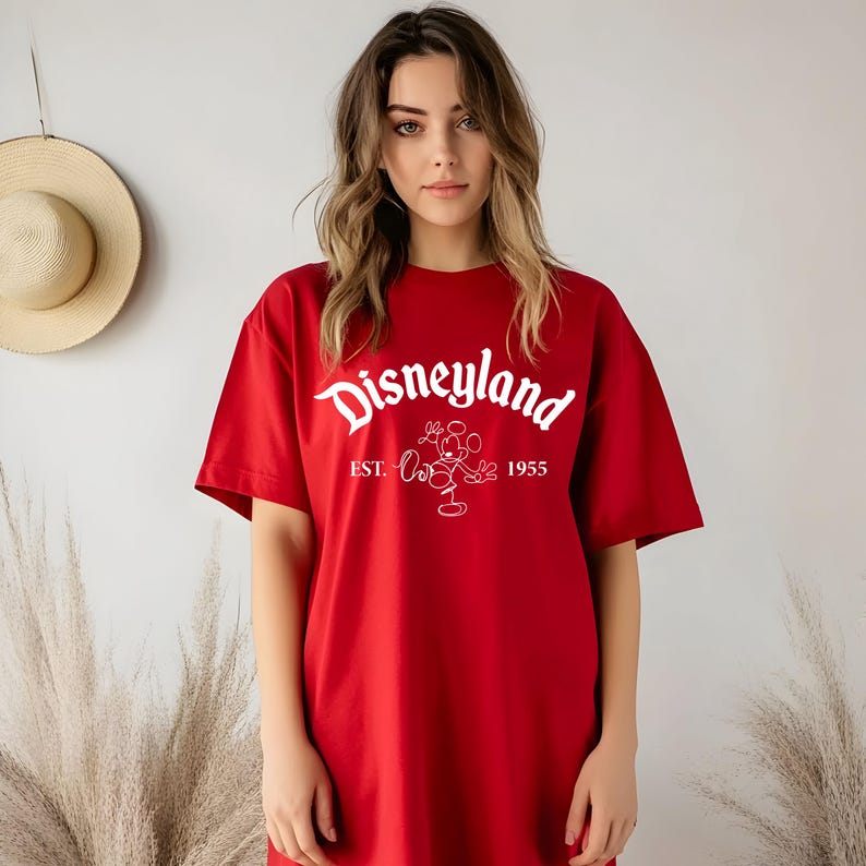 May include: Red t-shirt with a white graphic of Mickey Mouse and the text "Disneyland Est. 1955".