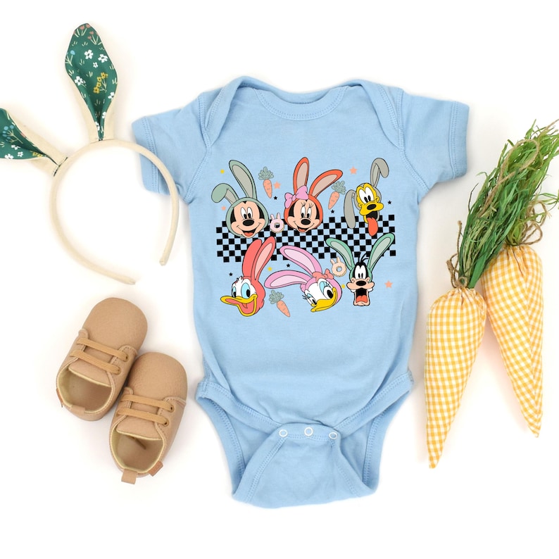 May include: Light blue baby onesie with a graphic of cartoon characters dressed as bunnies. The characters include Mickey Mouse, Minnie Mouse, Donald Duck, Goofy, and Pluto. The onesie has a checkered pattern and is surrounded by carrots and Easter grass.