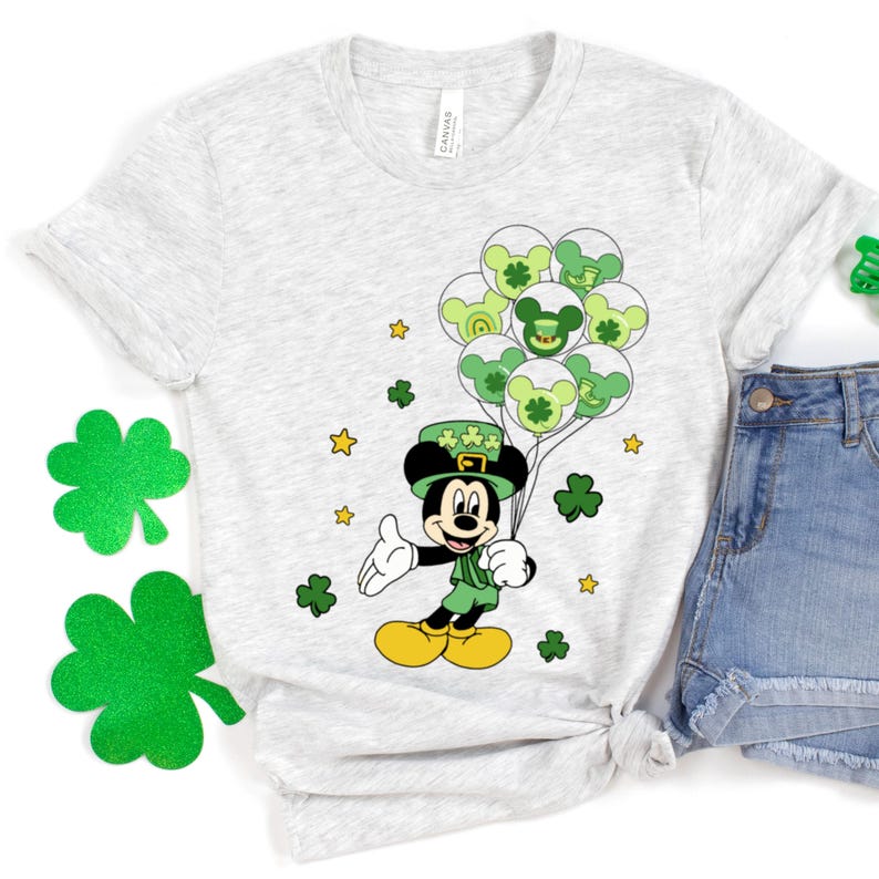 May include: A gray t-shirt with a green Mickey Mouse wearing a green hat and holding green balloons with shamrocks. The balloons have a green, white, and yellow color scheme.