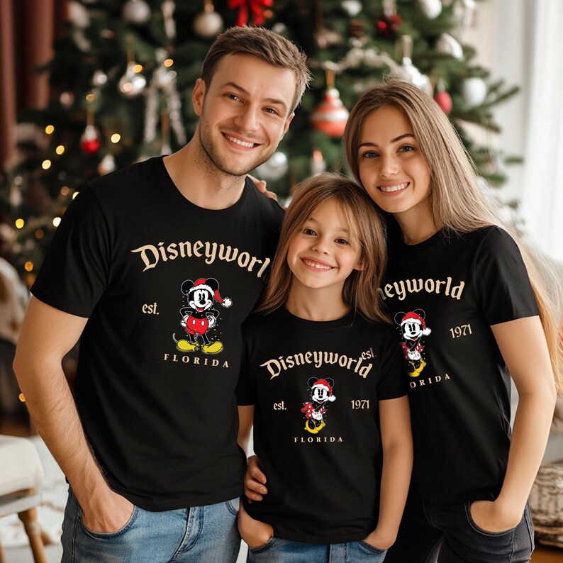 May include: A family of three wearing black t-shirts with a gold Mickey Mouse design. The shirts say "Disneyworld est. 1971 Florida".