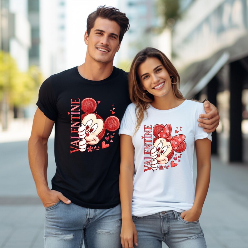 May include: Black and white t-shirts with Valentine's Day graphics. The black shirt features Mickey Mouse, red hearts, and the word "VALENTINE". The white shirt has Minnie Mouse, a red bow, and the word "VALENTINE".