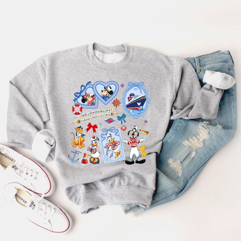 May include: A gray sweatshirt with a colorful print of Mickey Mouse, Minnie Mouse, Donald Duck, Goofy, and Pluto. The print features nautical themes like anchors, life preservers, and a cruise ship.