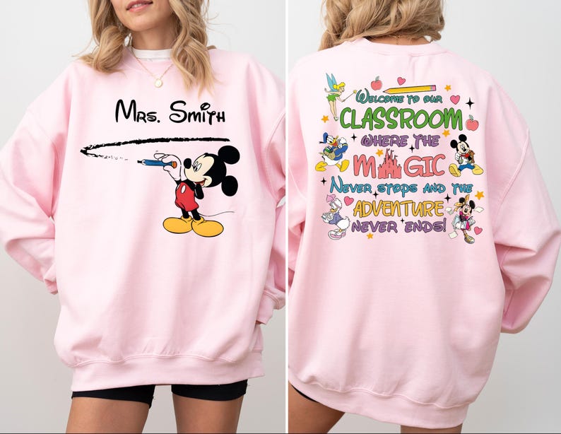 May include: Pink sweatshirt with a Mickey Mouse design on the front and a Disney-themed quote on the back. The quote reads "Welcome to our classroom where the magic never stops and the adventure never ends!"