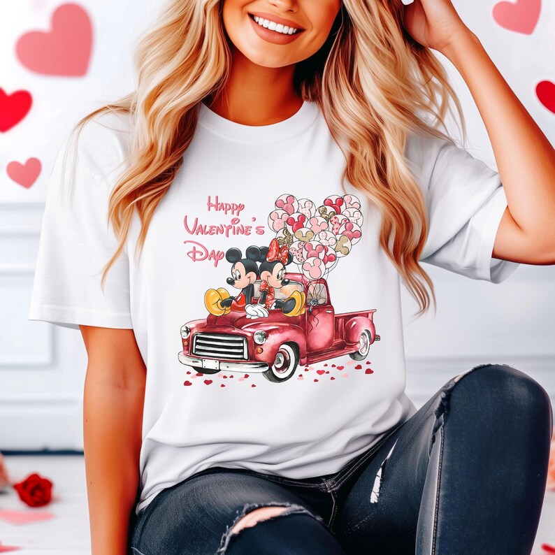 May include: White t-shirt with a graphic of Mickey and Minnie Mouse in a red pickup truck with pink heart balloons. The text "Happy Valentine's Day" is above the image.