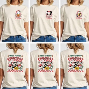 May include: Cream-colored t-shirts featuring Disney characters in Christmas attire. The front of the shirts display Donald Duck, Mickey Mouse, and Pluto. The back of the shirts have a larger graphic with multiple characters and the text "Very Merry Christmas."