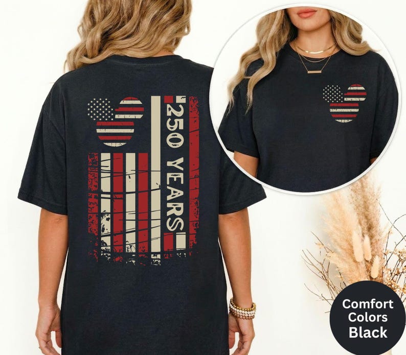 May include: Black t-shirt with a distressed American flag design and the text "250 YEARS". The flag design includes Mickey Mouse ears. The shirt is part of the Comfort Colors collection.
