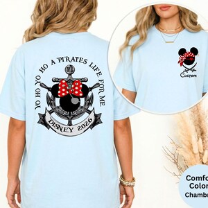 May include: Light blue t-shirt with a Disney pirate theme. The back features an anchor design with a Minnie Mouse bow, the text "Yo Ho Ho A Pirates Life For Me", and "Disney 2026". The front has a pirate Mickey Mouse head and the word "Custom".