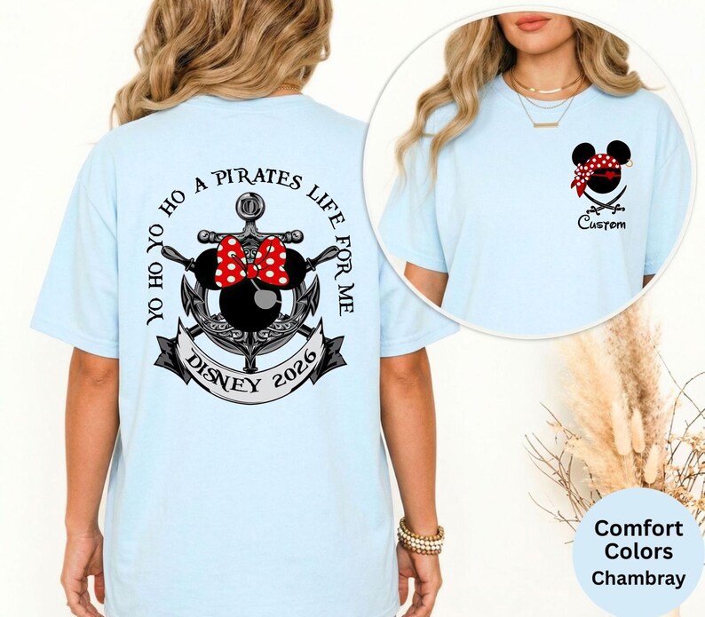 May include: Light blue t-shirt with a Disney pirate theme. The back features an anchor design with a Minnie Mouse bow, the text "Yo Ho Ho A Pirates Life For Me", and "Disney 2026". The front has a pirate Mickey Mouse head and the word "Custom".