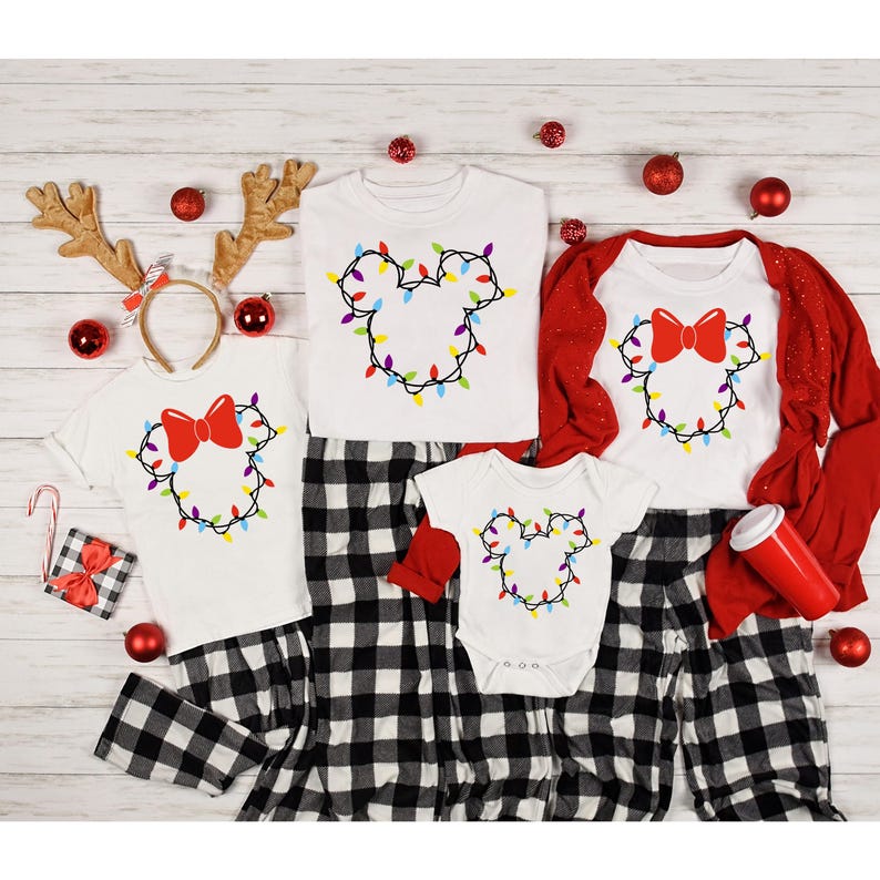 May include: A family matching Christmas pajama set with a white background and a red bow. The pajamas feature a Mickey Mouse silhouette made of colorful Christmas lights.