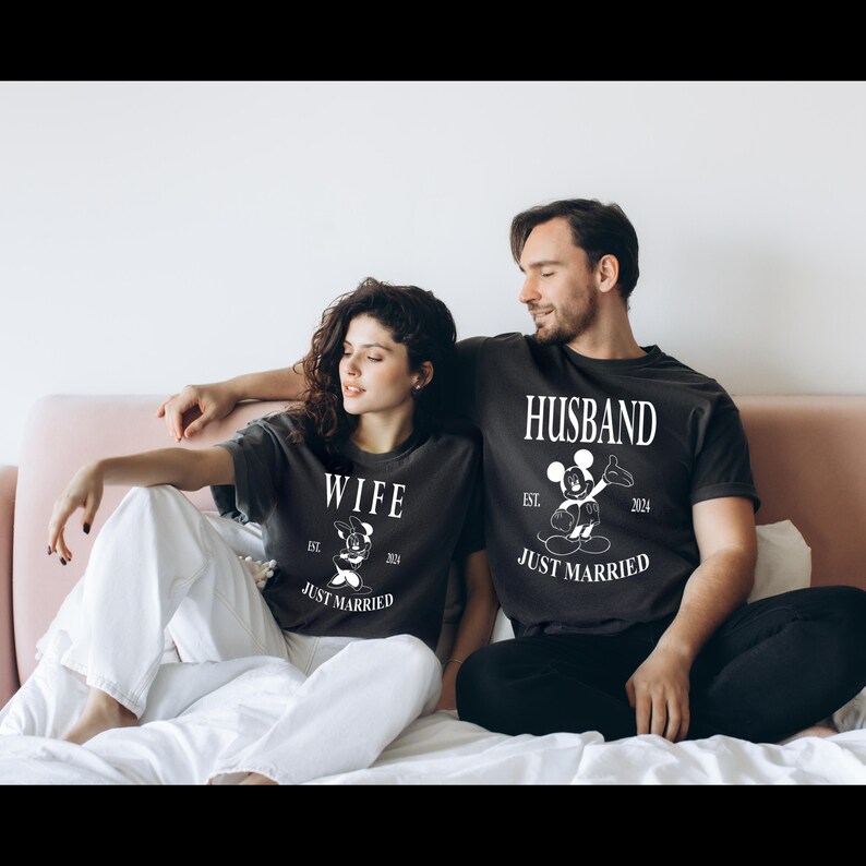 May include: A couple wearing matching black t-shirts with a Mickey Mouse and Minnie Mouse graphic. The shirts say "Husband" and "Wife" with the year "2024" and "Just Married".