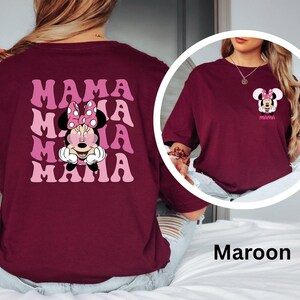 Puede incluir: Camiseta color granate con un dise&ntilde;o de Minnie Mouse. La parte delantera de la camiseta tiene un peque&ntilde;o dise&ntilde;o de Minnie Mouse y la palabra "MAMA". La parte trasera de la camiseta tiene la palabra "MAMA" repetida cuatro veces con un dise&ntilde;o de Minnie Mouse en el centro.