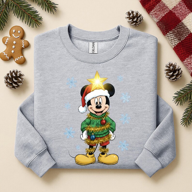 Pode incluir: Um moletom cinza claro com um design do Mickey Mouse com tema natalino. Mickey est&aacute; vestido como uma &aacute;rvore de Natal, usando um gorro de Papai Noel e uma estrela. O design inclui flocos de neve e decora&ccedil;&otilde;es festivas.