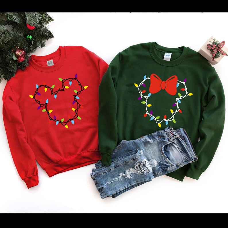 May include: Two Christmas themed sweatshirts, one red and one green, with a Mickey Mouse and Minnie Mouse design made of colorful Christmas lights.