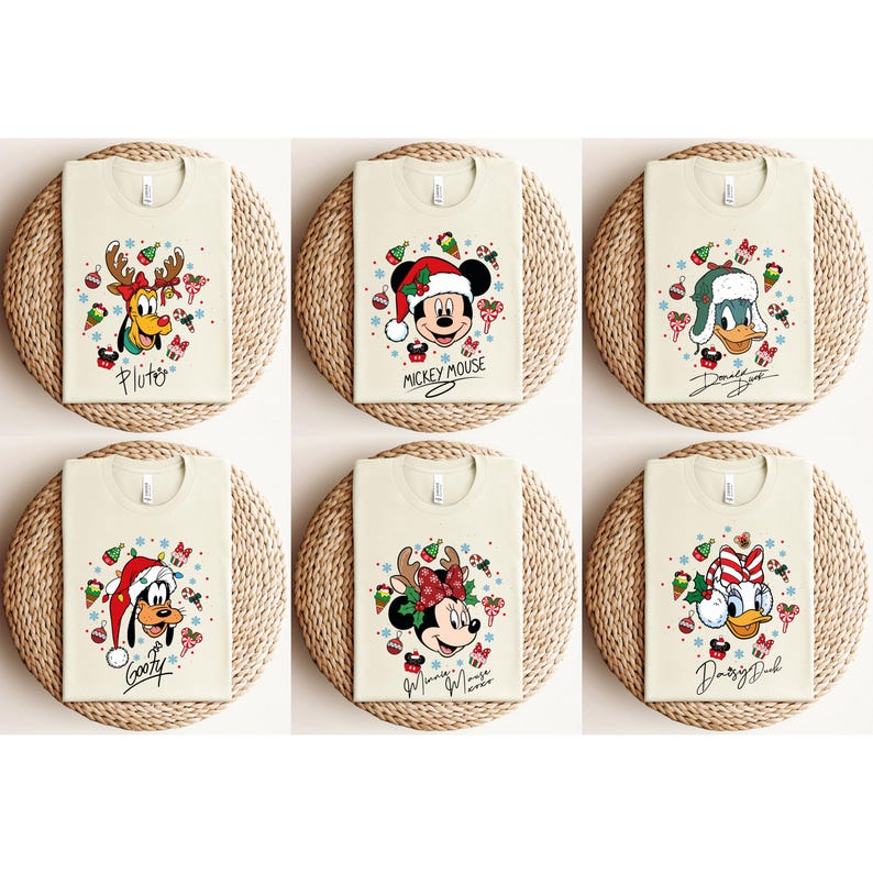 May include: Six cream-colored t-shirts featuring Disney characters in festive Christmas designs. Each shirt displays a different character: Pluto, Mickey Mouse, Donald Duck, Goofy, Minnie Mouse, and Daisy Duck, all wearing holiday attire. The shirts are arranged on woven mats.