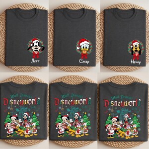 Op de afbeelding: Donkergrijze t-shirts met Disney-personages in kerstmutsen en kransen. E&eacute;n shirt toont Goofy met de naam "Jeff", een ander Donald Duck met "Casey", en een derde Pluto met "Henry". Andere shirts tonen een Disney World-ontwerp.