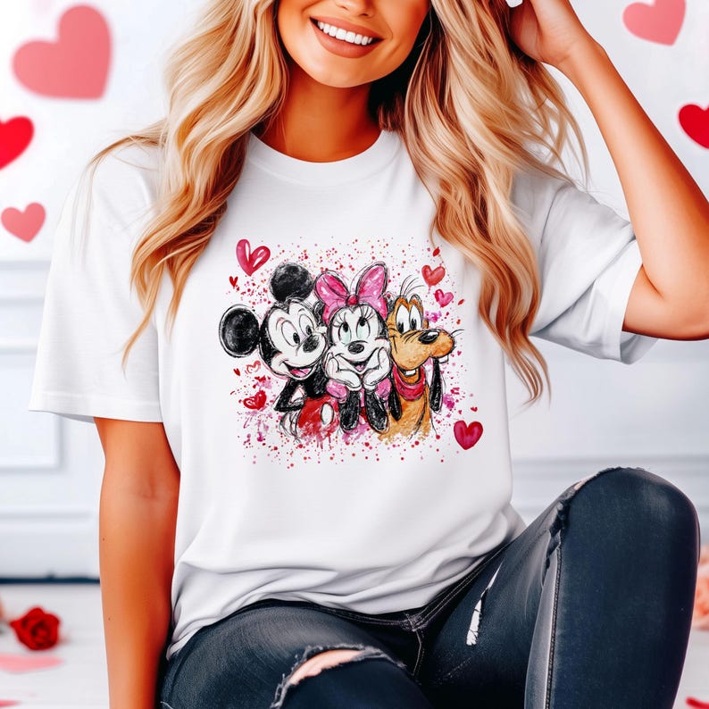 May include: White t-shirt featuring Mickey Mouse, Minnie Mouse, and Pluto with red heart accents. The graphic has a watercolor effect with red paint splatters. The characters are smiling and embracing, perfect for Valentine's Day.