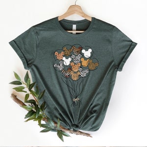 Puede incluir: Una camiseta verde con un gr&aacute;fico de cabezas de Mickey Mouse en forma de globos. Los globos est&aacute;n impresos con patrones de estampado animal, incluyendo cebra, leopardo y jirafa.