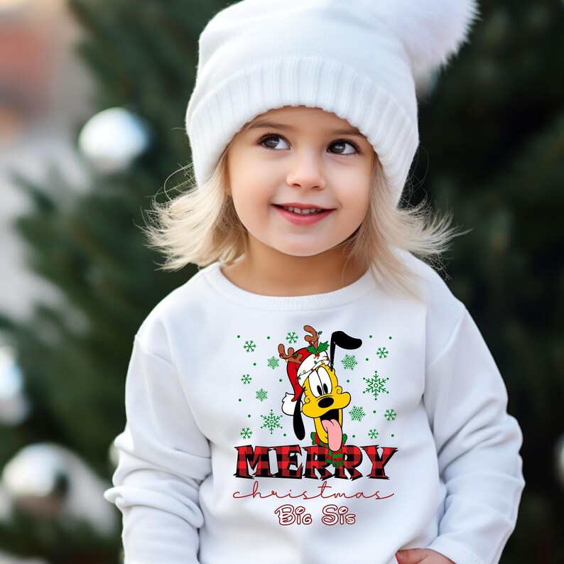 May include: White sweatshirt with a cartoon dog wearing a Santa hat and reindeer antlers. The dog is sticking its tongue out. The text "Merry Christmas Big Sis" is printed on the sweatshirt.
