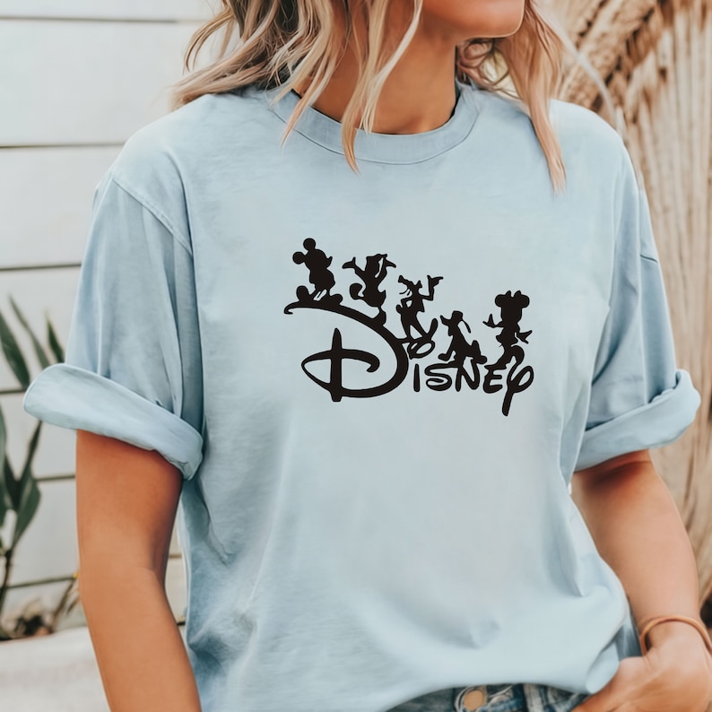 May include: Light blue t-shirt with a black silhouette of Mickey Mouse and friends walking on the Disney logo.