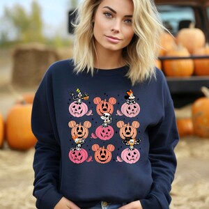 May include: A navy blue sweatshirt with a Halloween-themed design featuring Mickey Mouse, Minnie Mouse, Donald Duck, Goofy, and Pluto characters dressed in costumes and sitting on pumpkins.