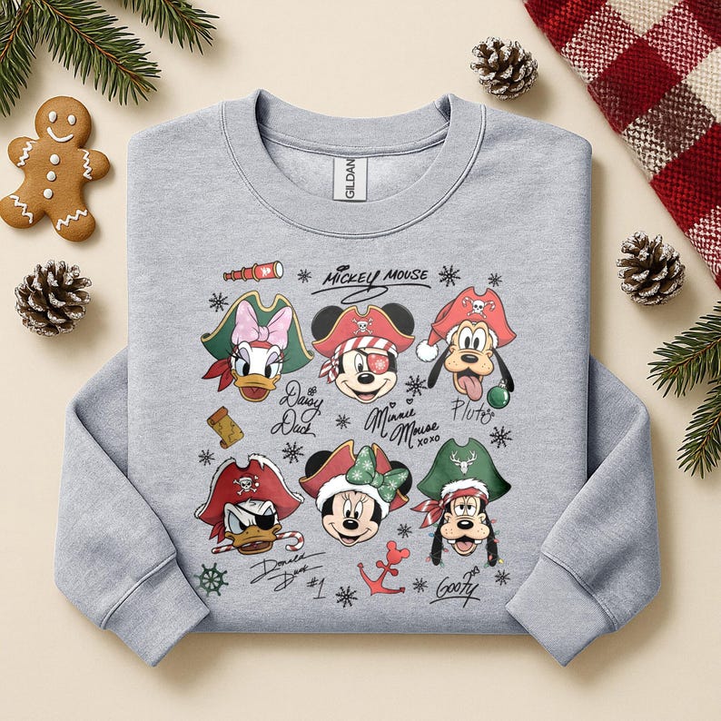 May include: A light gray sweatshirt featuring a graphic of Mickey Mouse and friends dressed as pirates. The design includes Daisy Duck, Mickey Mouse, Minnie Mouse, Pluto, Donald Duck, and Goofy, with text and pirate-themed accents.