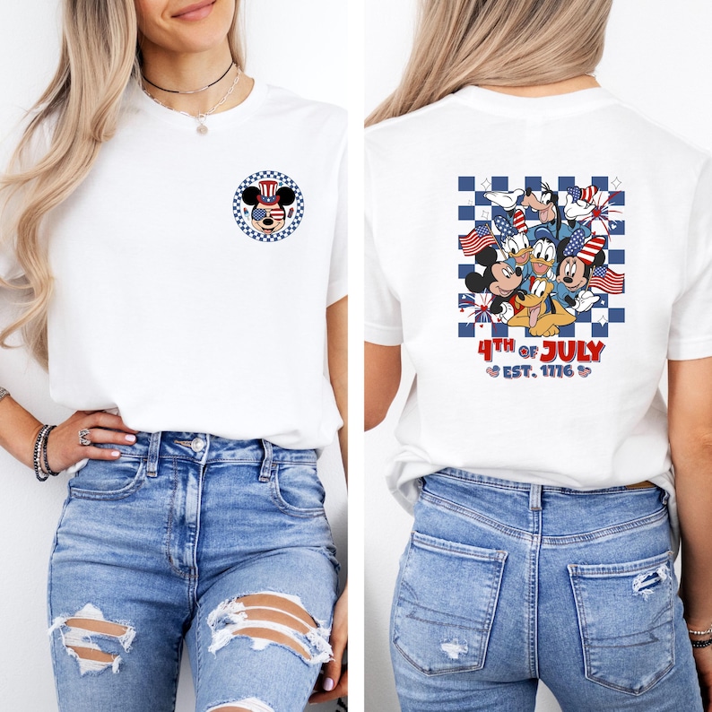 Puede incluir: Camiseta blanca con un dise&ntilde;o patri&oacute;tico de Mickey Mouse en la parte delantera y personajes de Disney con banderas en la parte trasera. La camiseta tiene el texto "4th of July EST. 1776". La camiseta se combina con vaqueros azules.