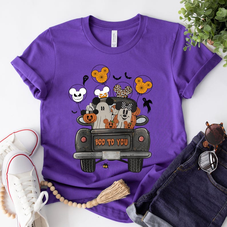 Peut inclure: T-shirt violet avec un motif sur le th&egrave;me d'Halloween repr&eacute;sentant Mickey et Minnie habill&eacute;s en fant&ocirc;mes dans un pick-up avec des citrouilles. Le texte "BOO TO YOU" est imprim&eacute; sur le camion.